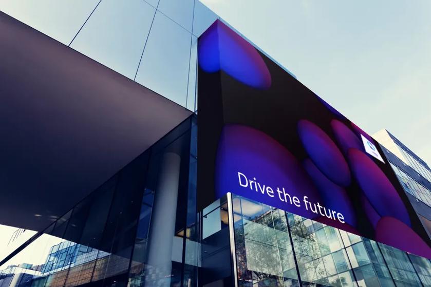 A sleek office building with a large LG direct view LED display. It's showing an abstract purple background with white text reading Drive the future.