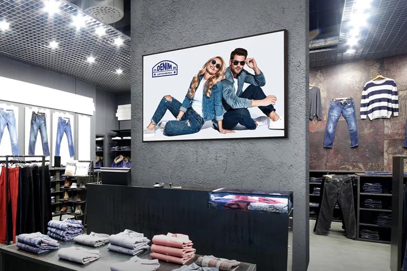 Interior of a modern clothing store showcasing a large denim ad and neatly displayed products.