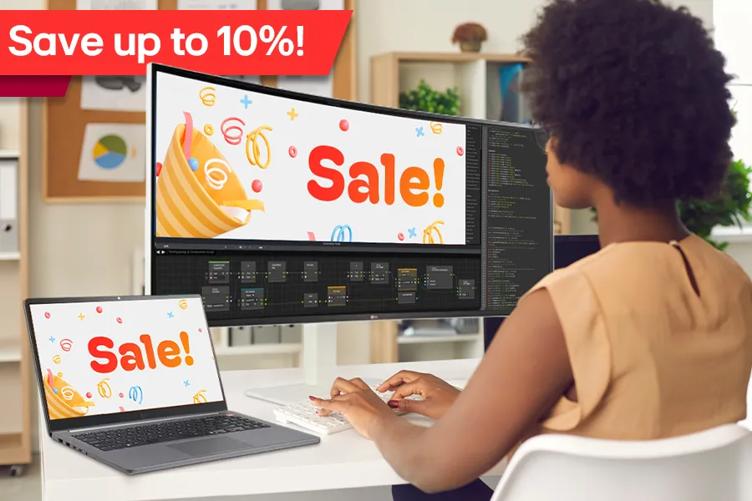 A woman at a desk works on her LG ultrawide monitor. The screen displays a work layout with a graphic of confetti and the words Buy More, Save More. The graphic is also displayed on the LG gram laptop next to the monitor on the desk. A banner in the corner of the image reads Save up to 10 percent!
