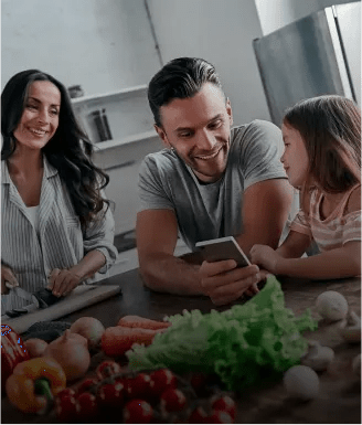 A family preparing food at the kitchen island while looking at the ThinQ recipe on a phone - mobile