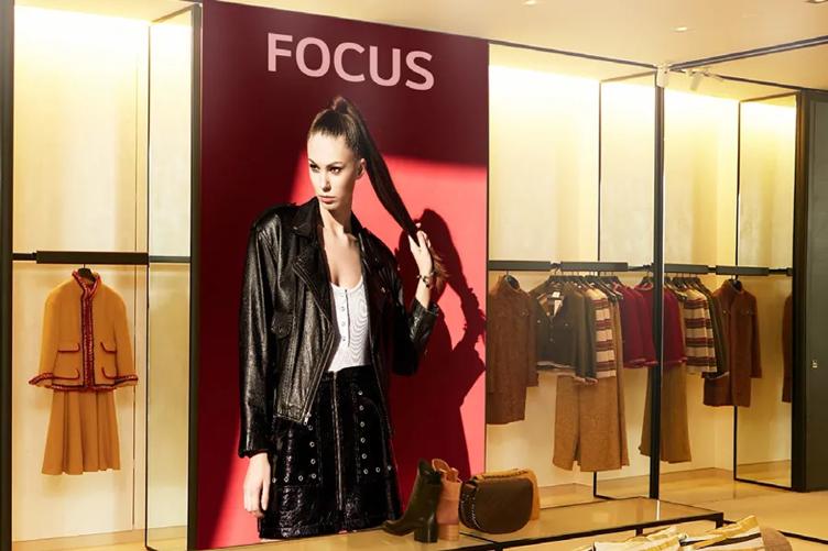 Clothing store interior with a large photo of a model in a black leather jacket and various garments on display.