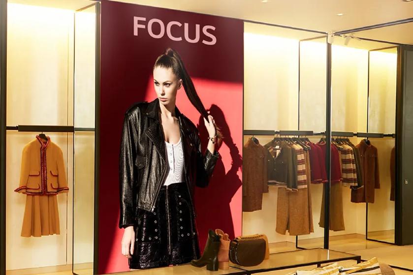 Clothing store interior with a large photo of a model in a black leather jacket and various garments on display.