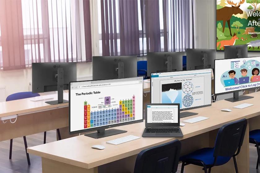 A classroom with LG Monitors on rows of desks, and an LG laptop. Digital signage on the wall welcomes students to the study space.
