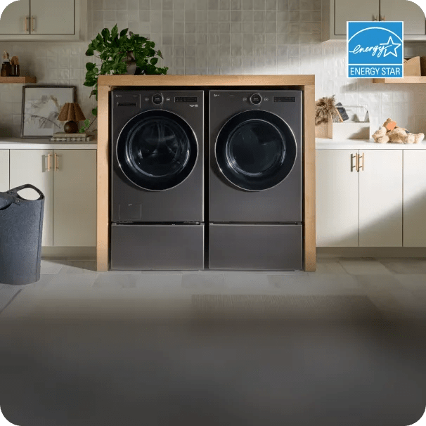 An LG front load washer and LG front load dryer sit next to each other in a brightly lit, modern laundry room with beige accents. A light blue badge with the ENERGY STAR® logo