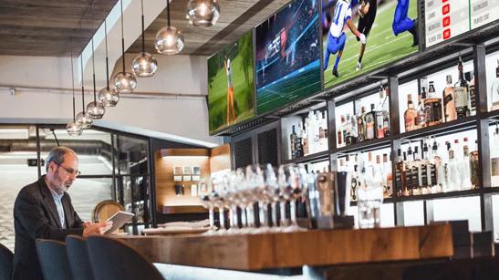 A customer uses his smart phone to select a live TV to listen to at the bar