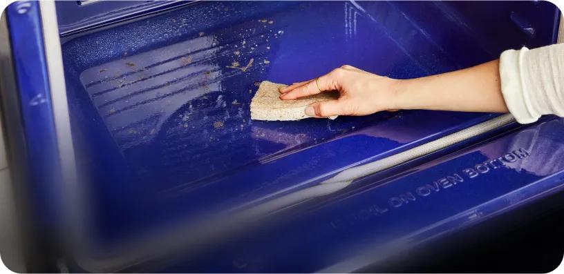 An arm wipes the inside of an LG wall oven with a sponge.