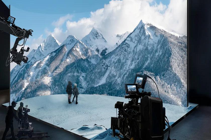 Film set with realistic mountain backdrop and filming equipment.