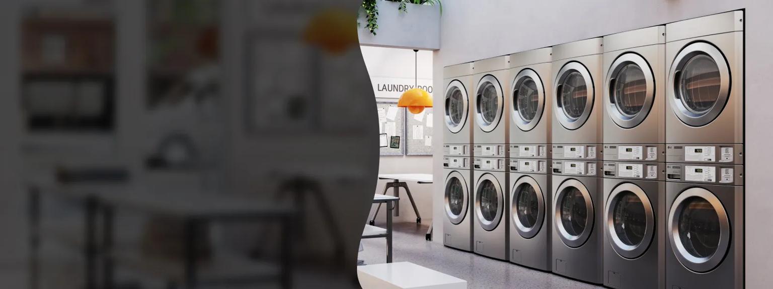 A row of six modern, stainless steel stacked LG commercial laundry machines in a clean, brightly lit laundry room.