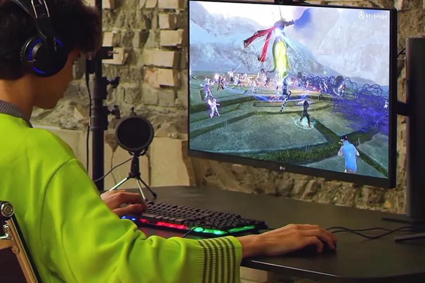 Person playing a video game on a computer with a bright green sweater and headphones.