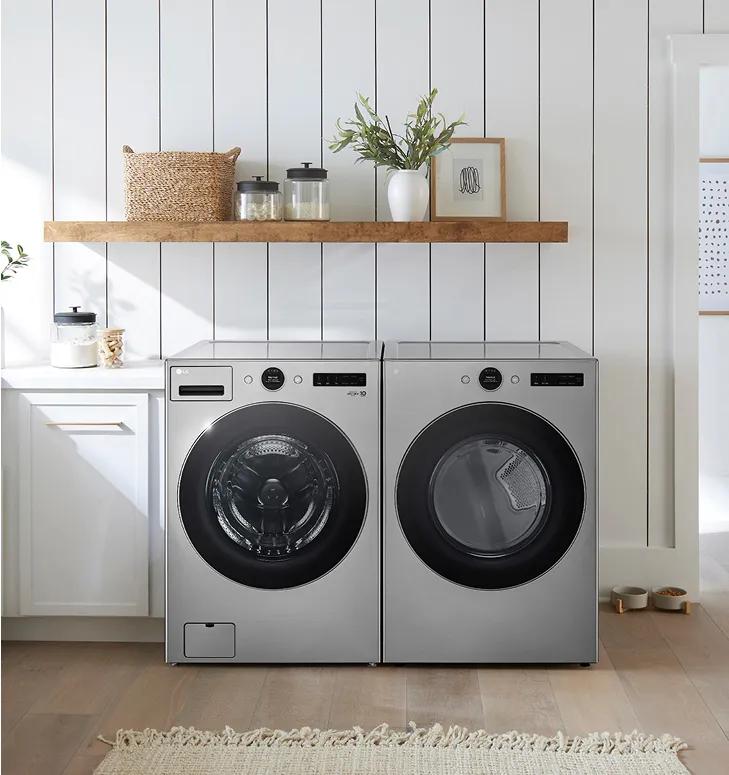 Silver front-load washer and dryer in a bright laundry room white cabinets and walls.