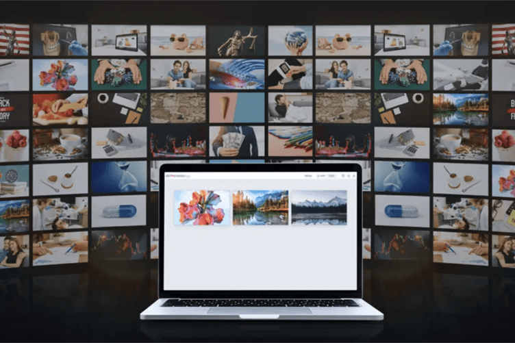 Laptop displaying abstract flowers and landscapes, in front of a large collage of varied images.