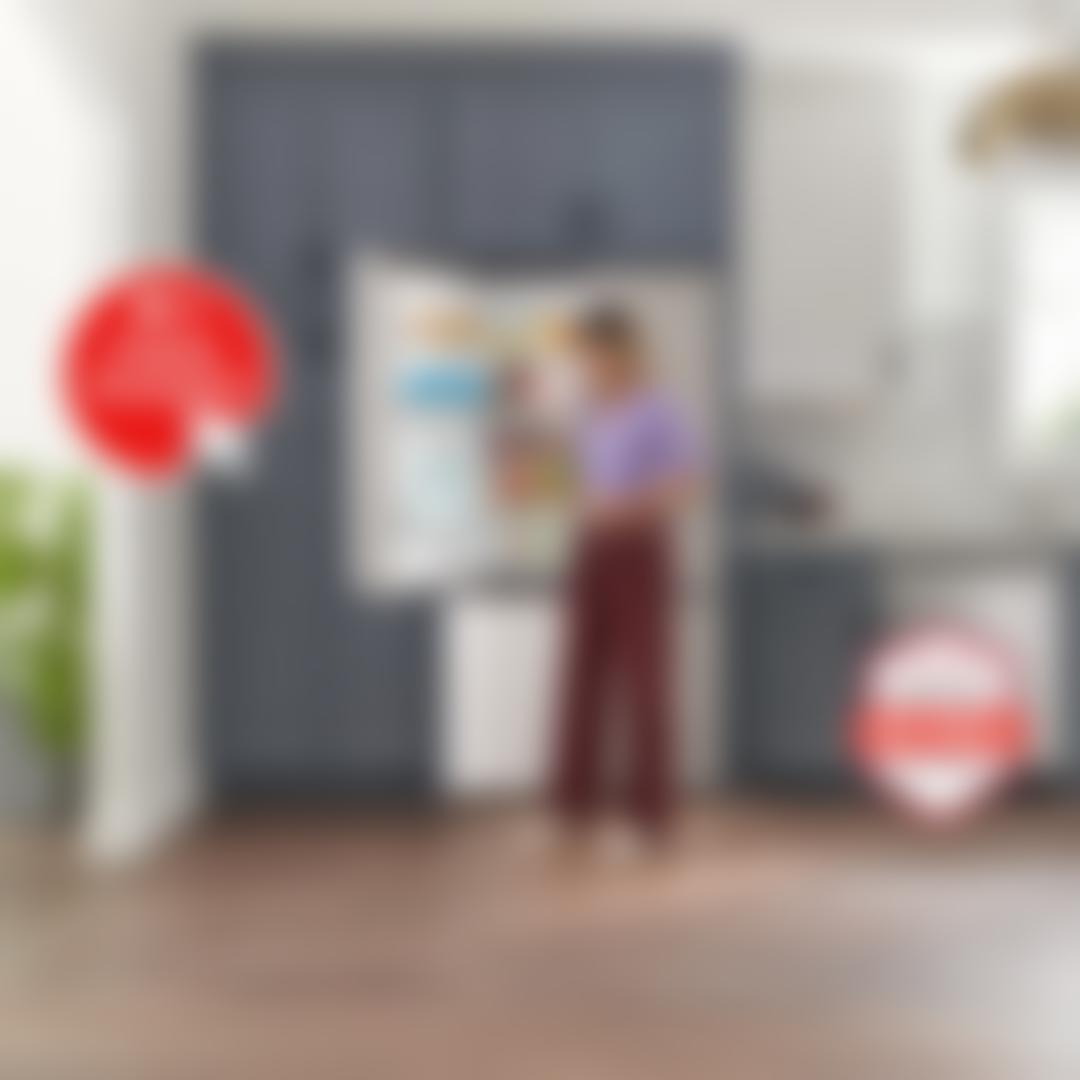 Woman in a purple top reaching into a built-in stainless steel LG bottom-freezer refrigerator stocked with drinks and produce, in a kitchen with navy cabinetry and hexagon tile backsplash. An "LG Online Exclusive" badge appears on the left, with an "America's Most Reliable Line of Appliances" badge on the right.