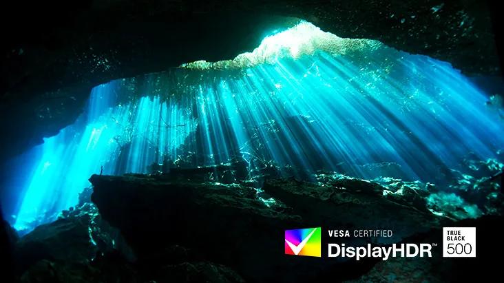Blue light from the cave illuminates the water, creating a serene and enchanting underwater scene, the VESA Display HDR logo is in the bottom left corner, showcasing clarity and stunning visuals offered by the LG gram