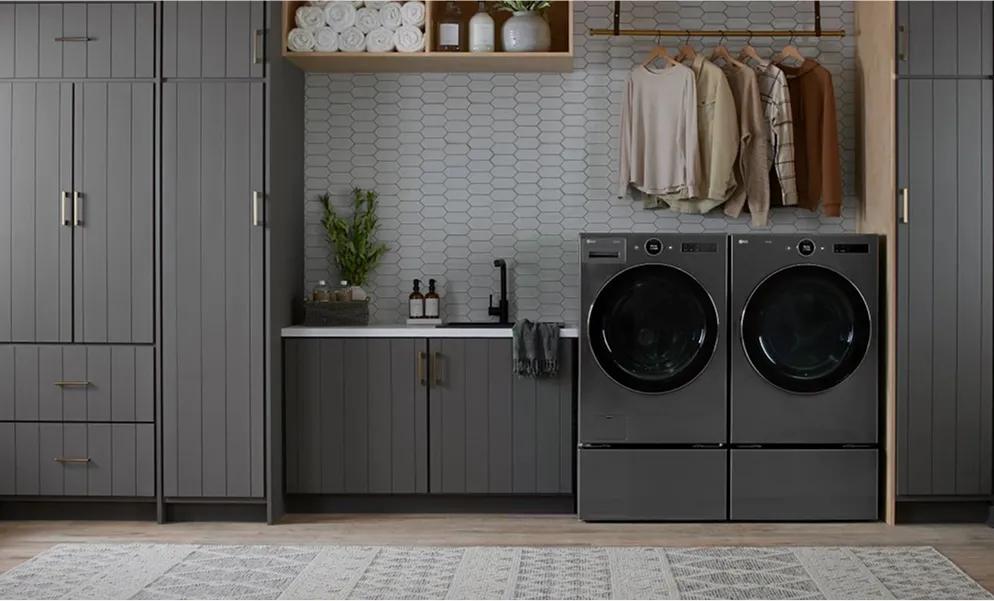 Dark gray front-load washer and dryer in a laundry room with dark gray cabinets.