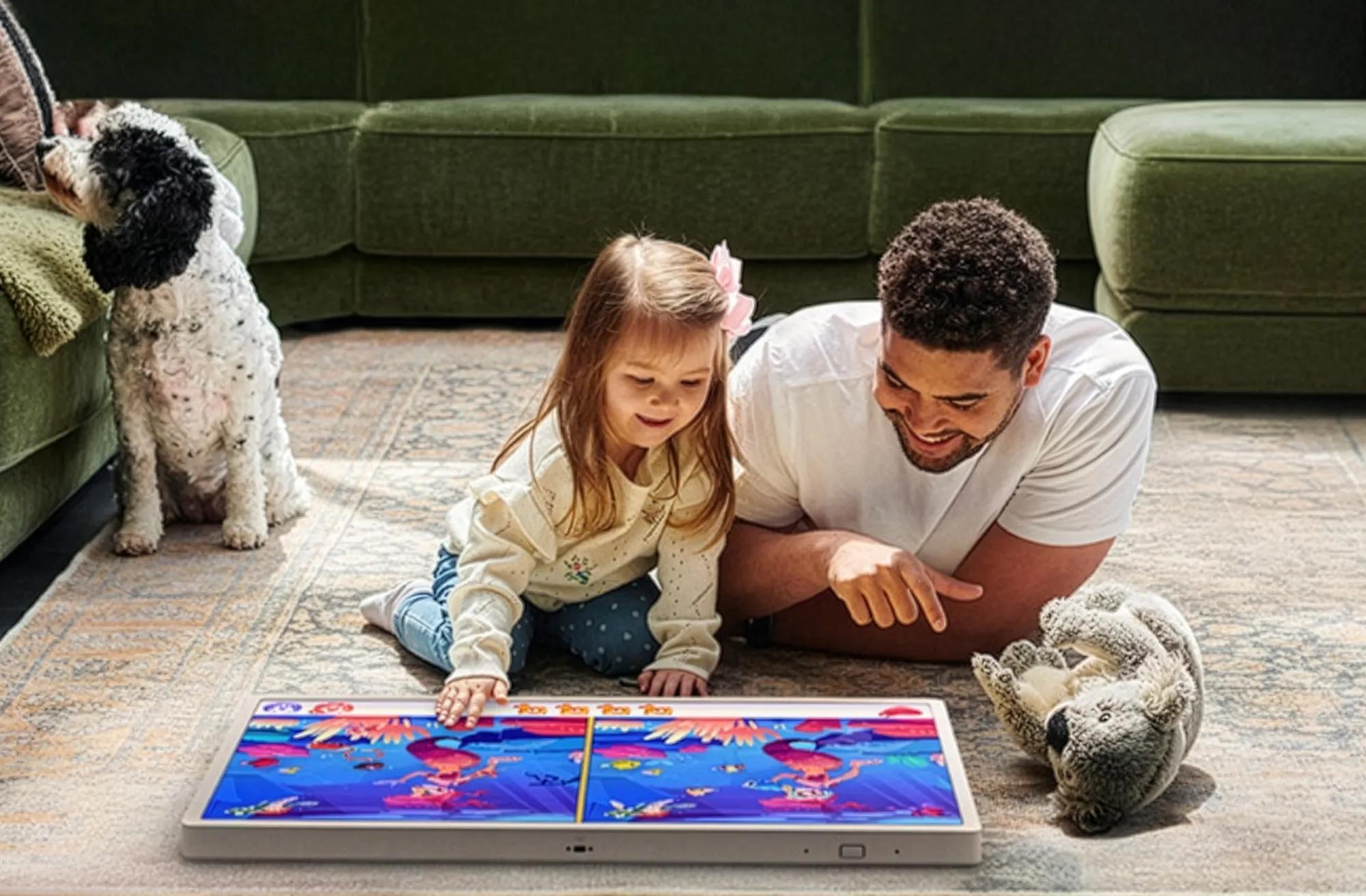 Father and daughter lying on the floor, playing a game on LG StanbyME 2 laid flat.