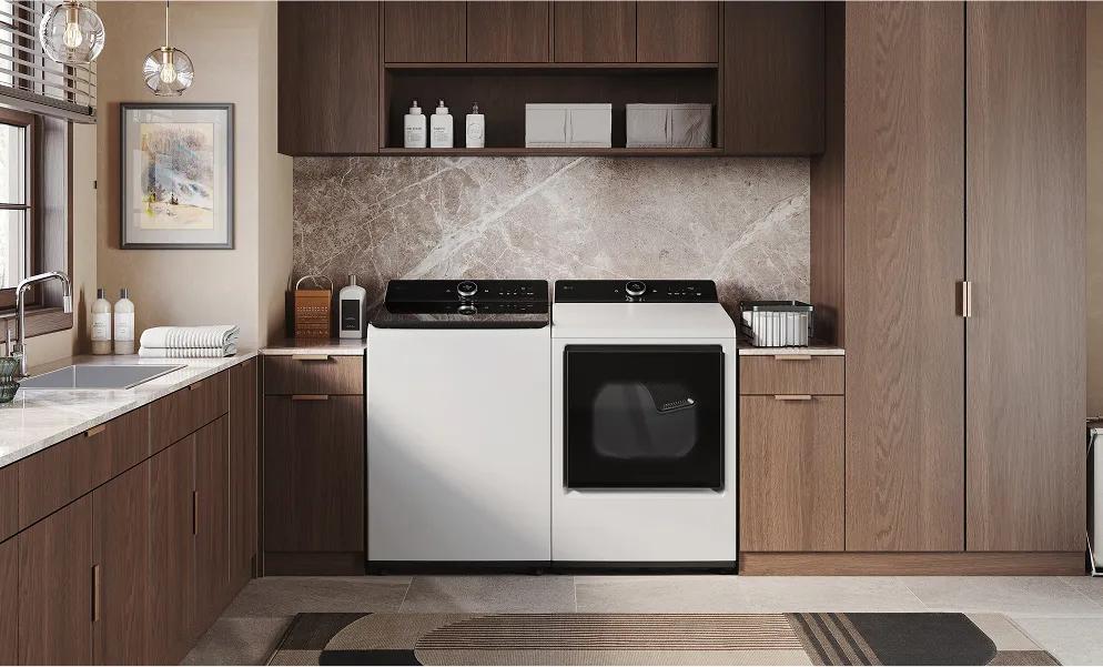 White top-load washer and white front-load dryer in a modern laundry room with brown cabinets around it.