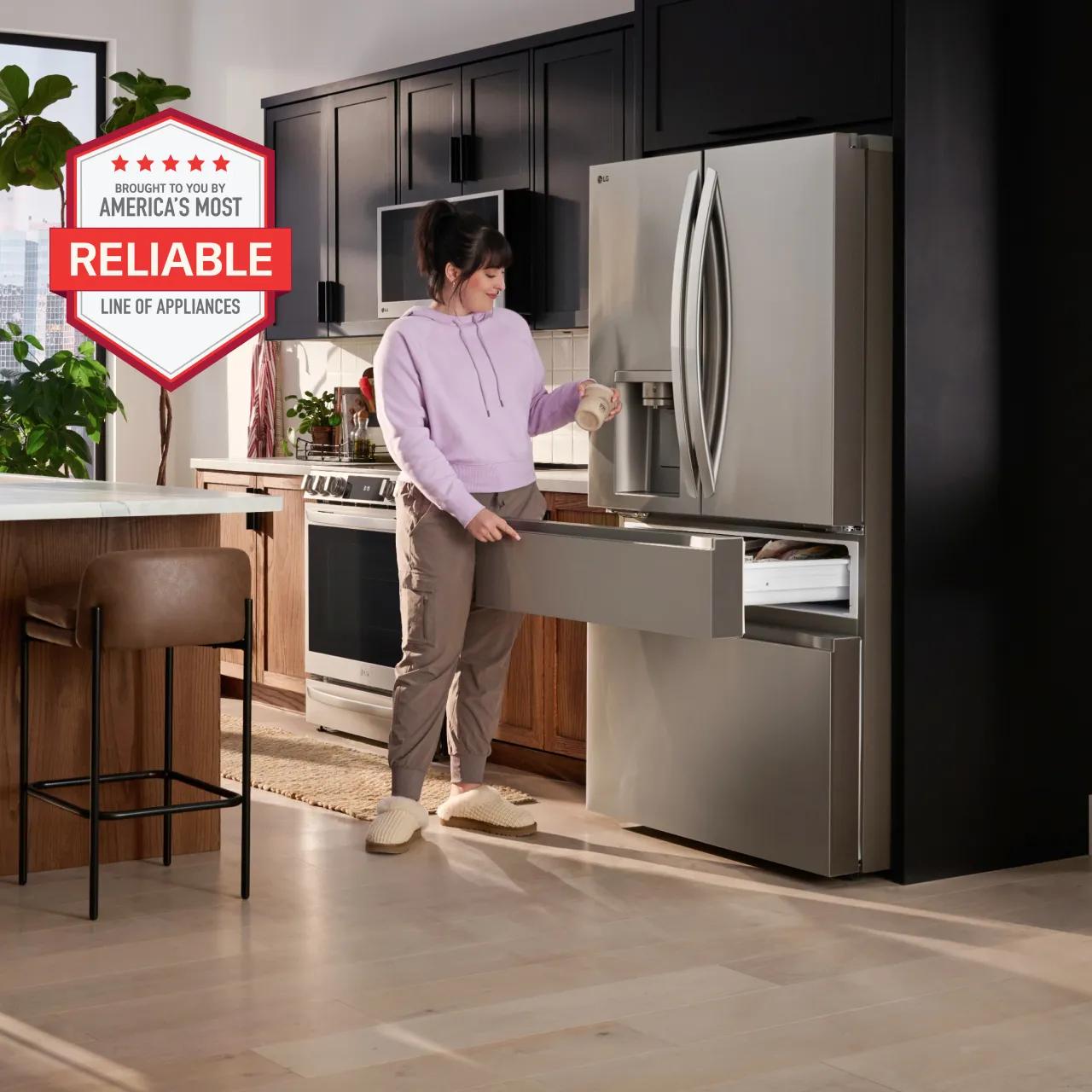 A woman stands beside a LG refrigerator in a modern kitchen setting, showcasing a America's most reliable LG home appliances.