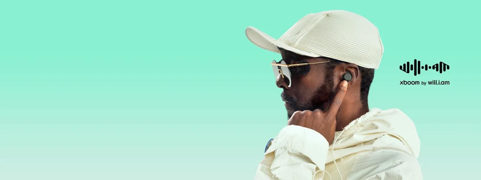 Image of will.i.am showing him with an earbud in his ear while touching it