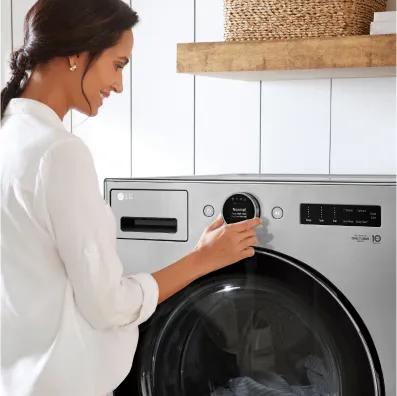 Woman adjust the controls on a silver front-load washer.