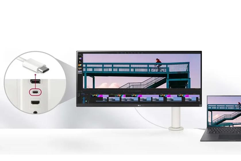 Ultrawide monitor and laptop connected via USB-C, showing video editing software with a bridge scene.