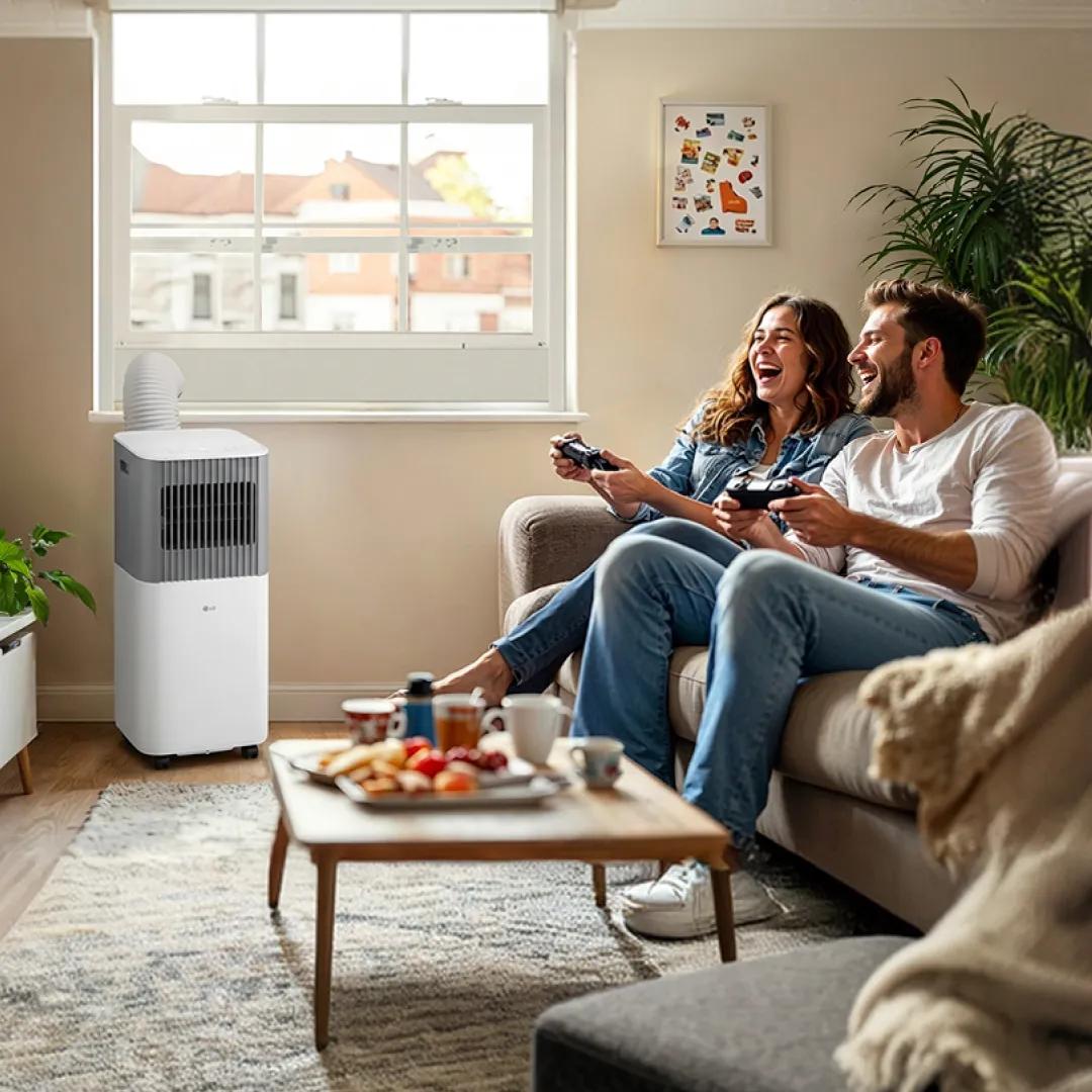 An LG portable air conditioner keeps a sunny living room cool as two people laugh and play video games together.