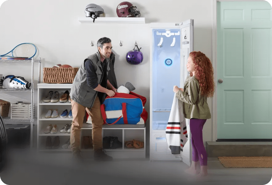 A father and daughter remove a hockey jersey from the LG Styler® as they pack a sports duffel bag.