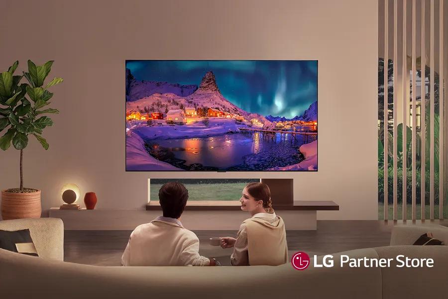 A woman chats with her friend in front of an LG fridge in a modern kitchen.