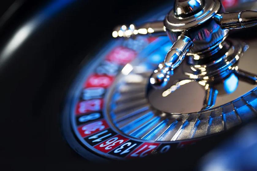 Close-up of a roulette wheel with metallic arms and illuminated blue center.