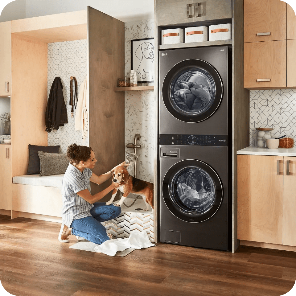 A woman washes her dog in the laundry room tub next to her LG WashTower™.