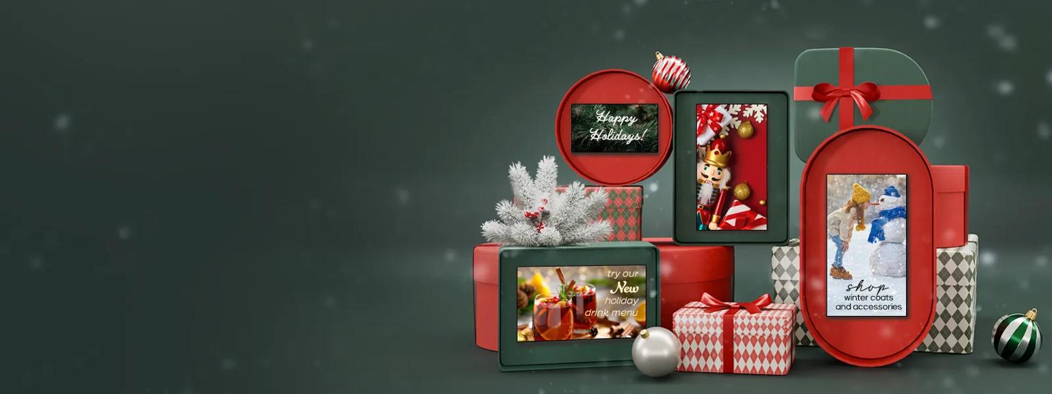 A pile of red and green wrapped holiday gifts on a green background. LG Digital Signage is displayed in the open gift boxes with winter-themed imagery on their displays. Snow drifts behind the scene.