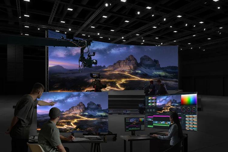 A film production set with a landscape scene on large monitors and a curved screen, featuring mountainous terrain under a starry sky.