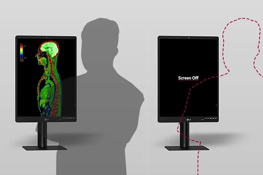 The image displays two LG diagnostic monitors placed side by side on stands against a light gray background. The monitor on the left shows a side view of a human body MRI scan in vivid colors, predominantly green, red, and blue. The colors represent different intensities or materials, as indicated by a small color gradient scale on the left of the screen. The monitor on the right is turned off and has the text "Screen Off" displayed in white on its black screen. Beside this monitor is a dashed, red outline of a person's silhouette, indicating the absence of a person.