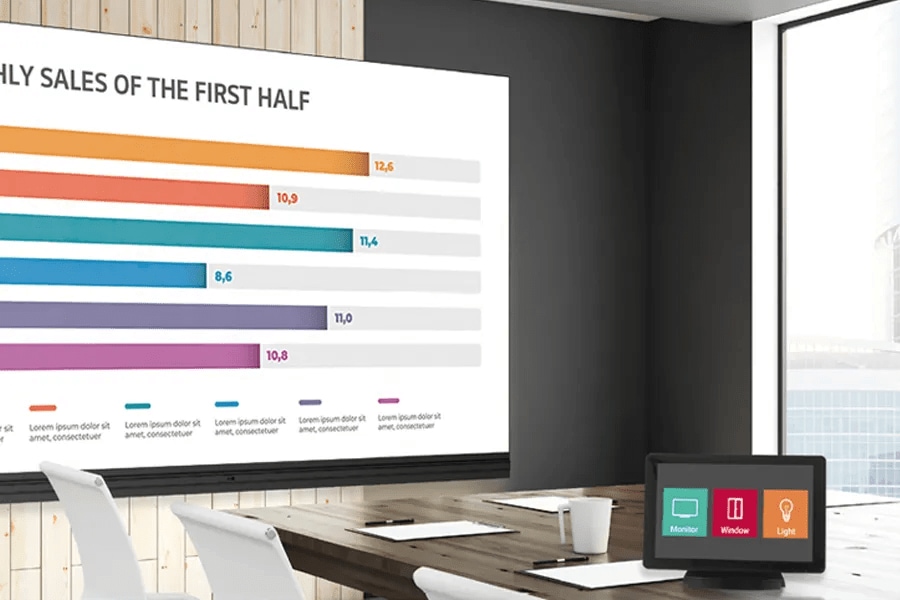 Conference room with a bar chart presentation on screen and a tablet on the table showing icons.