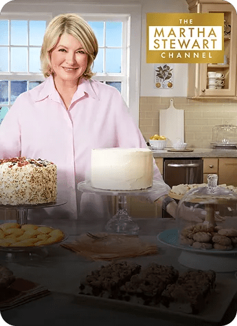 Martha Stewart stands in a kitchen behind several cakes and cookies for The Martha Stewart Channel.