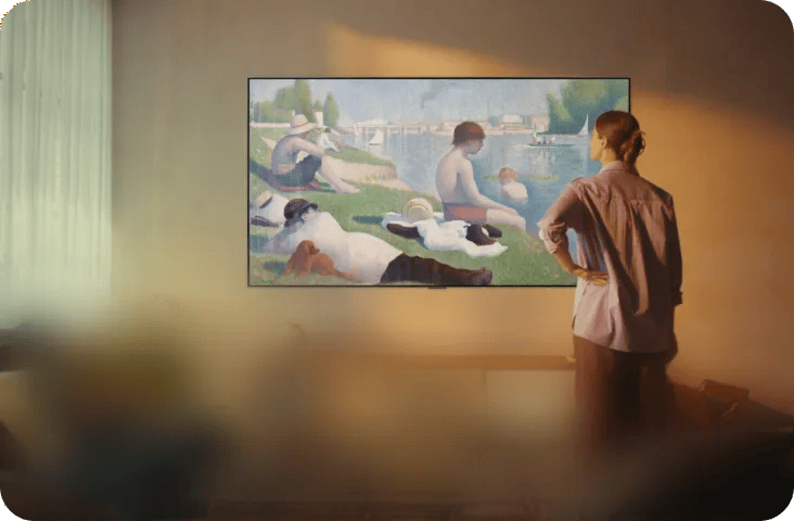 Woman viewing a classic painting displayed on an LG TV mounted on a wall in a room.