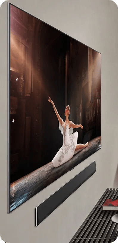 Wall-mounted LG TV showing a ballerina performing on stage with a sleek, ultra-think soundbar mounted below.