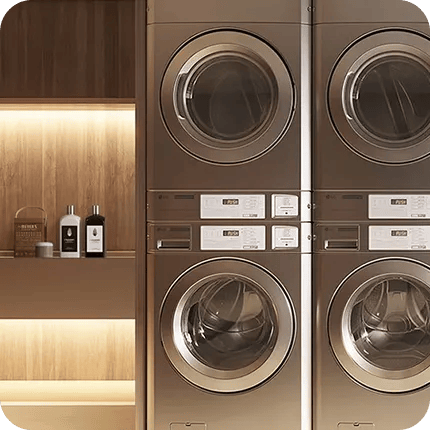 Two stacked LG commercial laundry units side by side in a professional laundry room setting with illuminated shelving.
