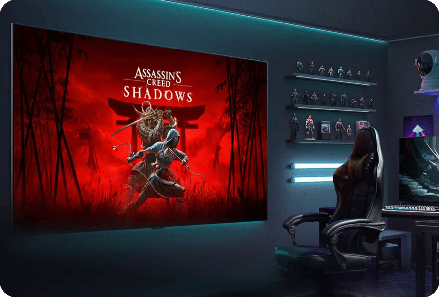 LG TV mounted on wall displaying Assassin's Creed Shadows game art in a room with a gaming chair, collectible figurines on shelves, and a desk with monitor setup
