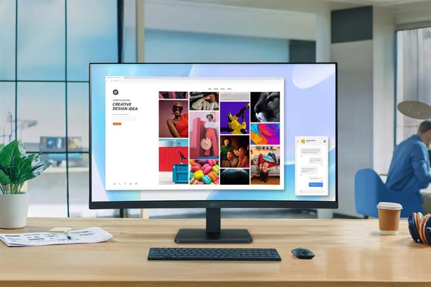 A modern office desk with a widescreen monitor displaying a colorful webpage, surrounded by a keyboard, mouse, plant, and coffee cup.