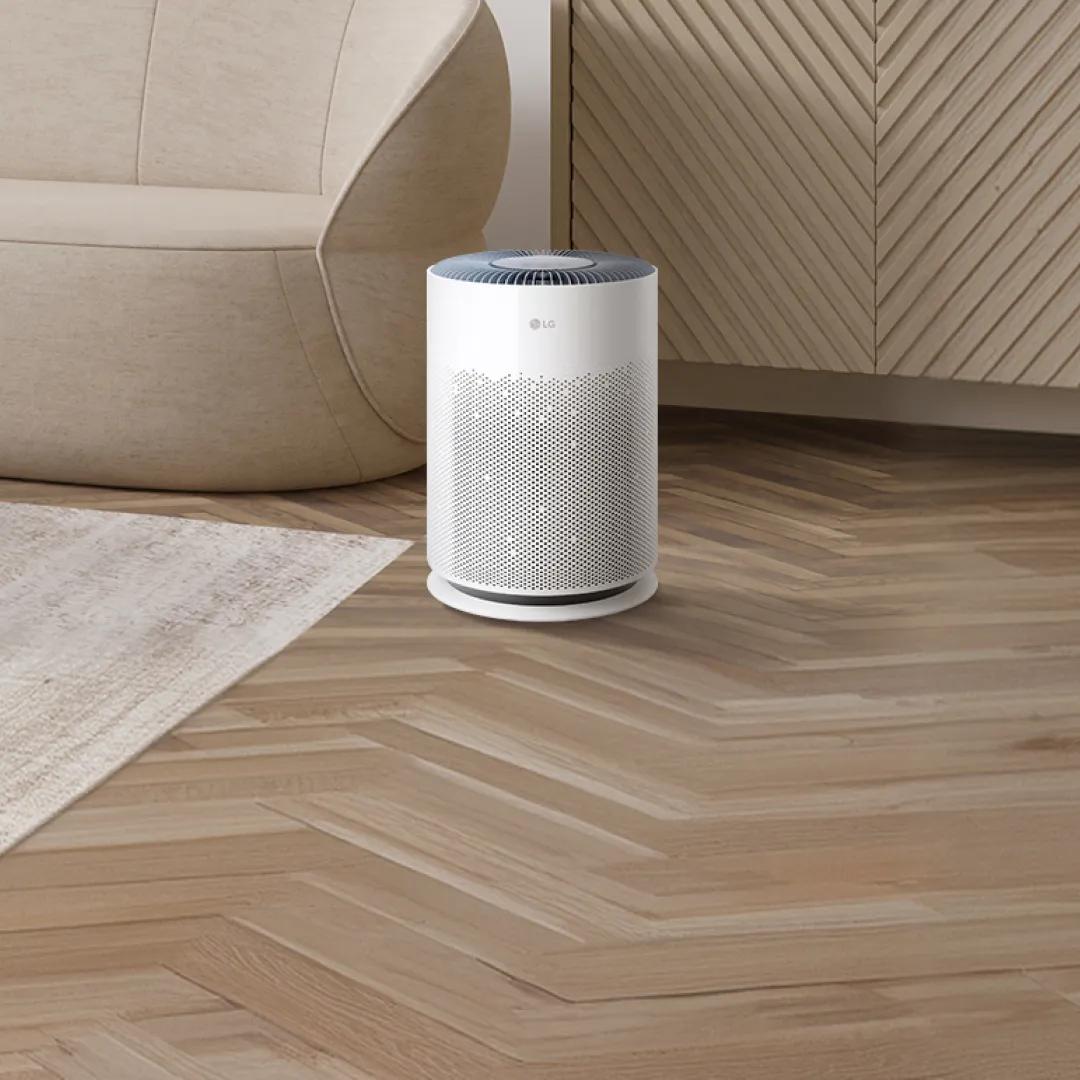 LG PuriCare air purifier in a living room next to a rounded sofa and area rug
