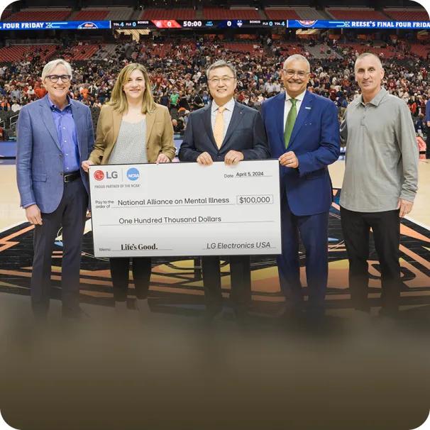 A photo from the 2024 NCAA Final Four shows LG executives presenting NAMI representatives with a check for 100000 dollars.