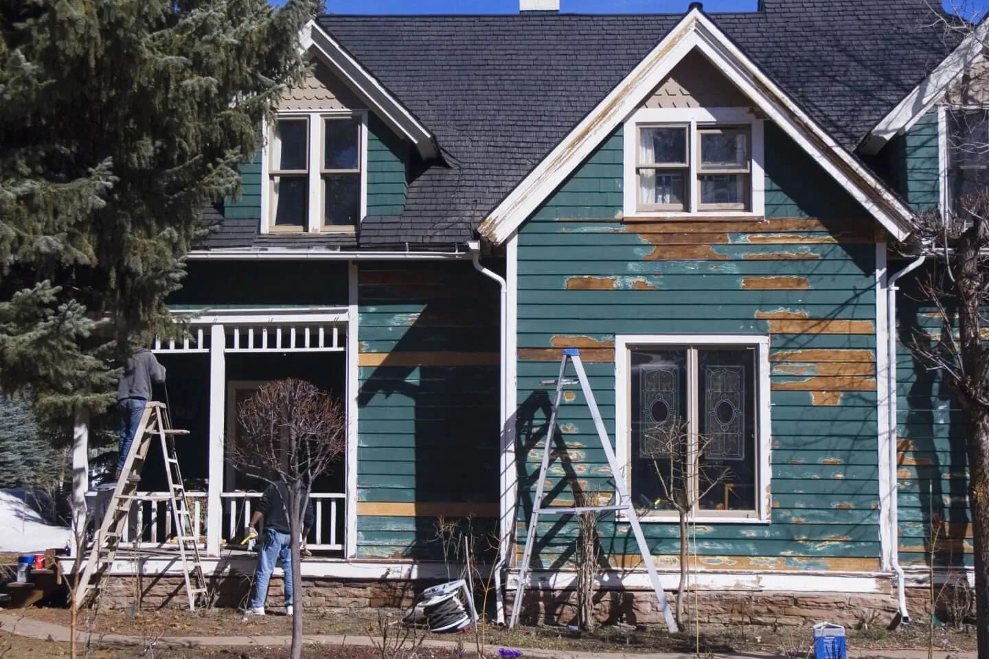 A green-painted house with a ladder leaning against it