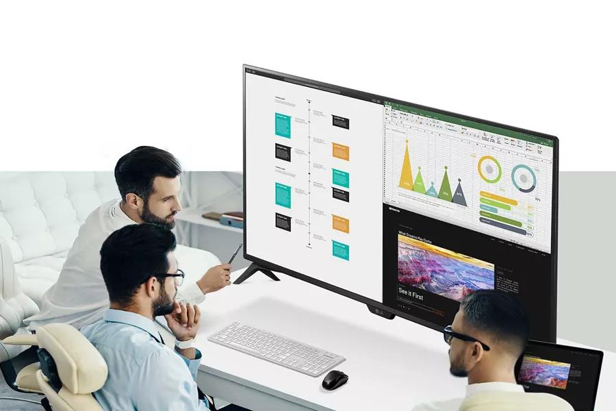Image of the 43UN700T B monitor on the desk and three men looking at the screen
