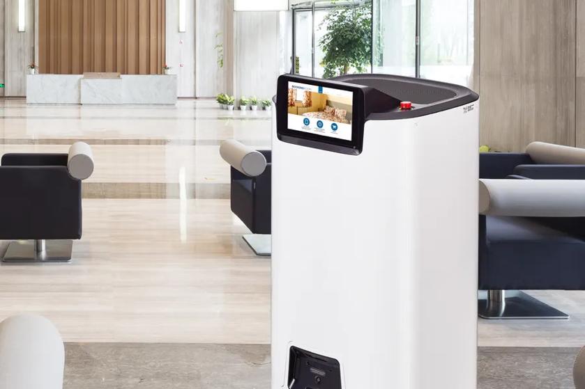 CLOi ServeBot drives through an upscale hotel lobby, with a brightly colored advertisement on her display.