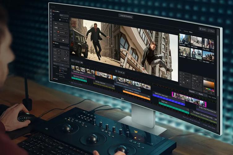 Person using video editing software on a widescreen monitor displaying urban and parkour scenes.