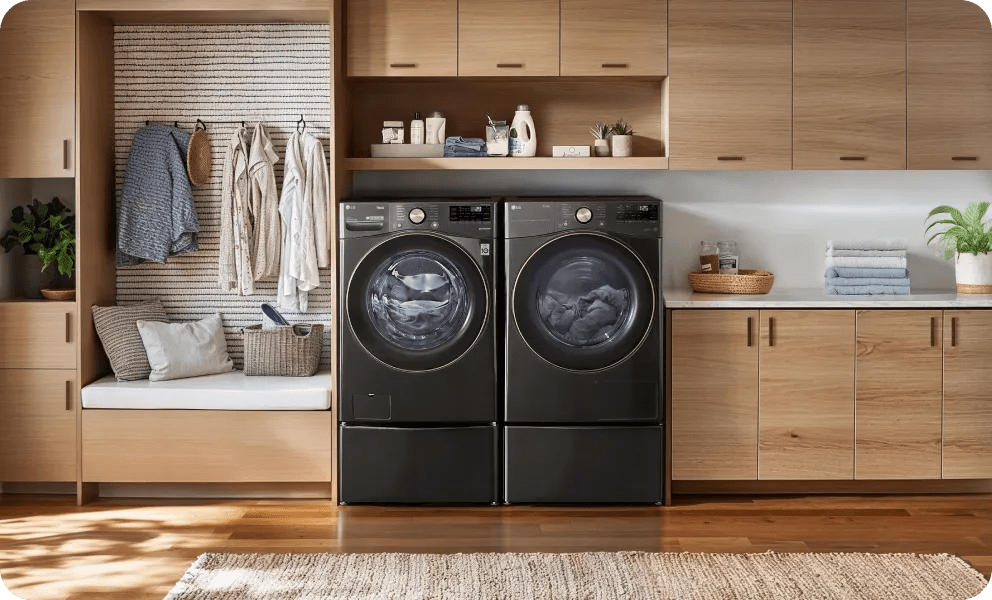 A black LG front load washer and LG front load dryer are in a wood-accented laundry room with a boho feel.