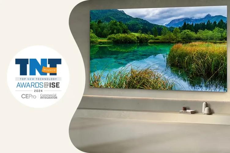 On the right side is an image of a warmly lit modern space with smooth grey walls and floor. An LG MAGNIT display is mounted on the wall, showing a vivid and detailed lake scene. To the left of this image is a white circle with an award graphic inside of it. The award graphic reads: Top New Technology Winner, Awards at ISE 2024. Below that are small logos for Commercial Integrator magazine and CEPro.
