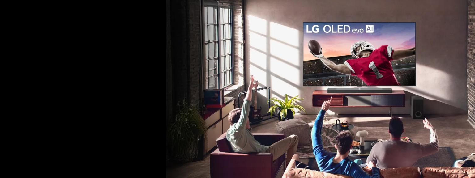 A group of men cheer from a bright living room as they watch a football game on an LG OLED TV. 
