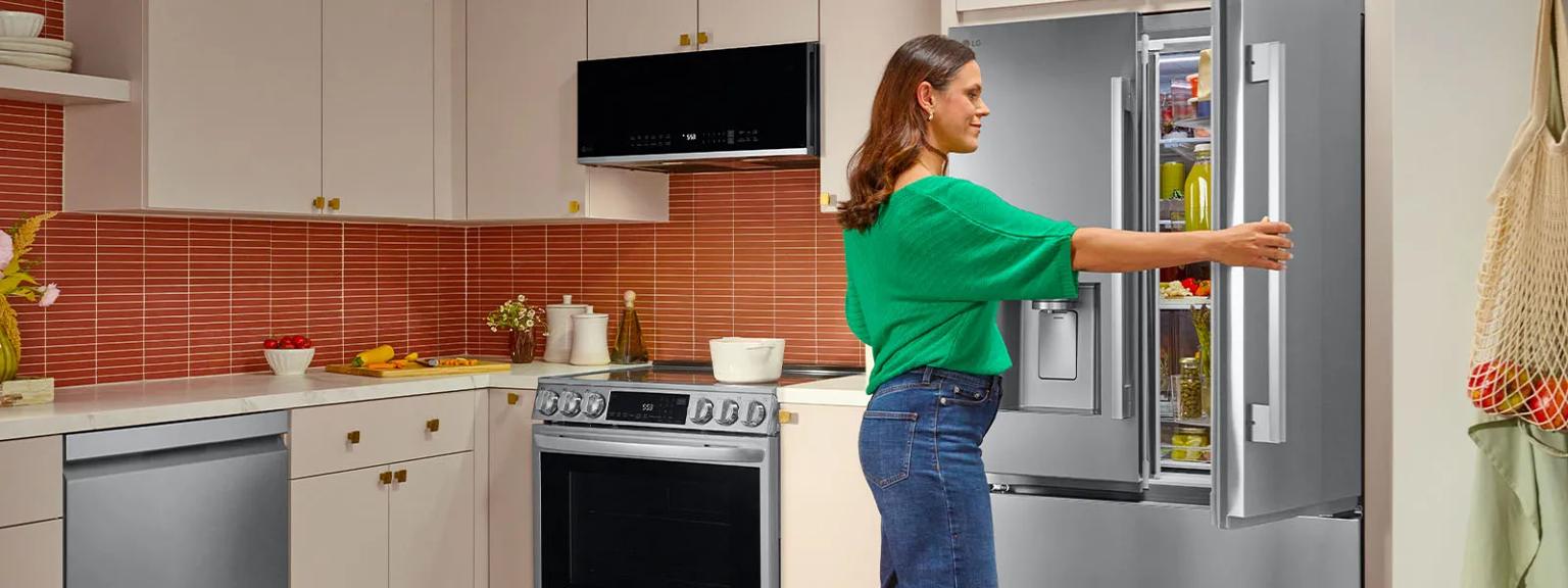Woman in kitchen holding open a French door refrigerator.