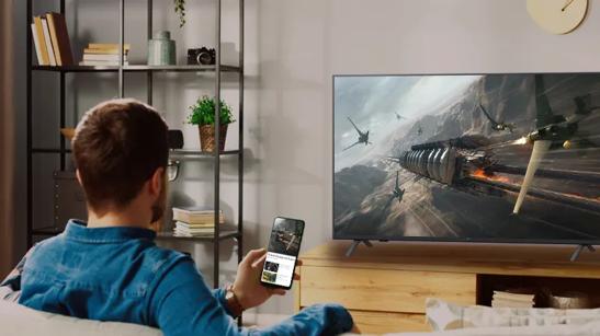 A man holds his phone up, using it to cast a movie to the LG hotel TV with Apple Airplay.